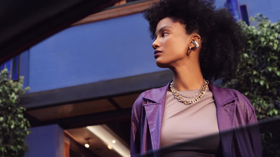 Woman wearing Bose Ultra Open Earbuds outside.