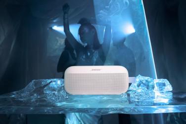 Bose SoundLink Flex Portable Speaker (2nd Gen) placed on ice with a woman dancing in the background